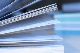 Primer plano de las páginas de un libro, ligeramente abiertas, con otros libros borrosos en el fondo.