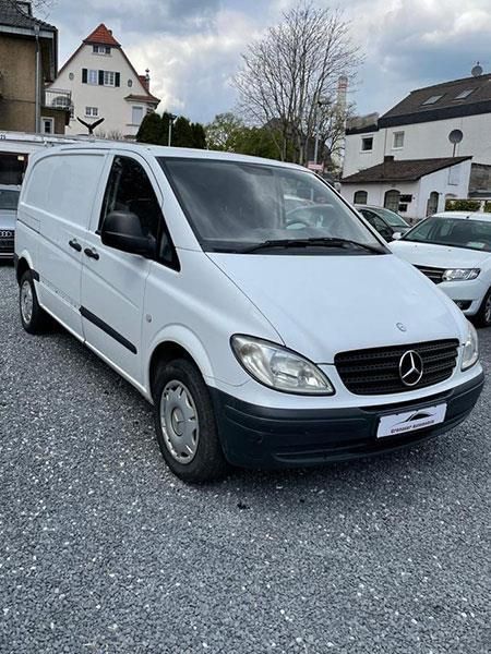Ein weißer Mercedes-Van steht auf einem Schotterplatz.