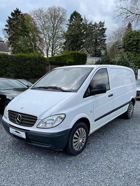 Ein weißer Mercedes-Van steht auf einem Schotterplatz.