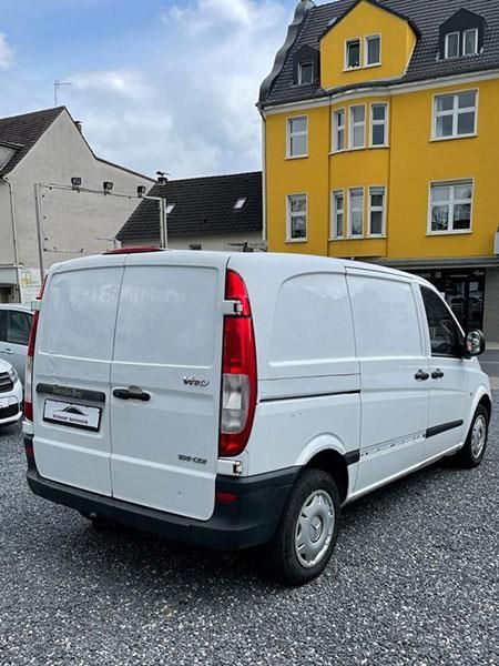 Ein weißer Lieferwagen steht vor einem gelben Gebäude