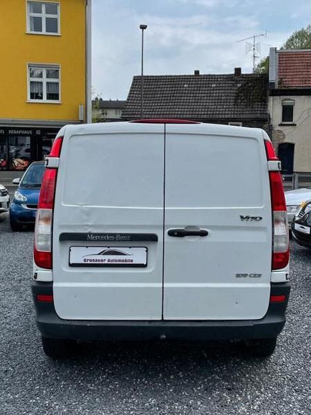 Ein weißer Lieferwagen steht vor einem gelben Gebäude