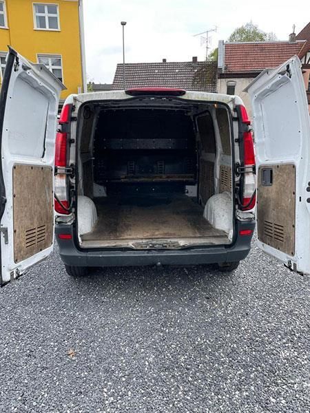 Ein weißer Lieferwagen steht mit offenen Türen auf einem Schotterplatz.