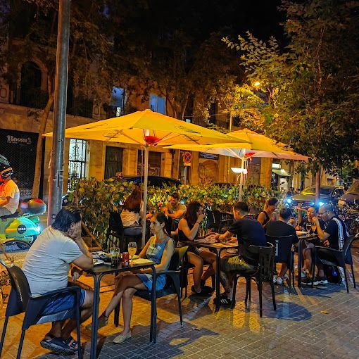Un grupo de personas están sentadas en mesas bajo sombrillas amarillas.
