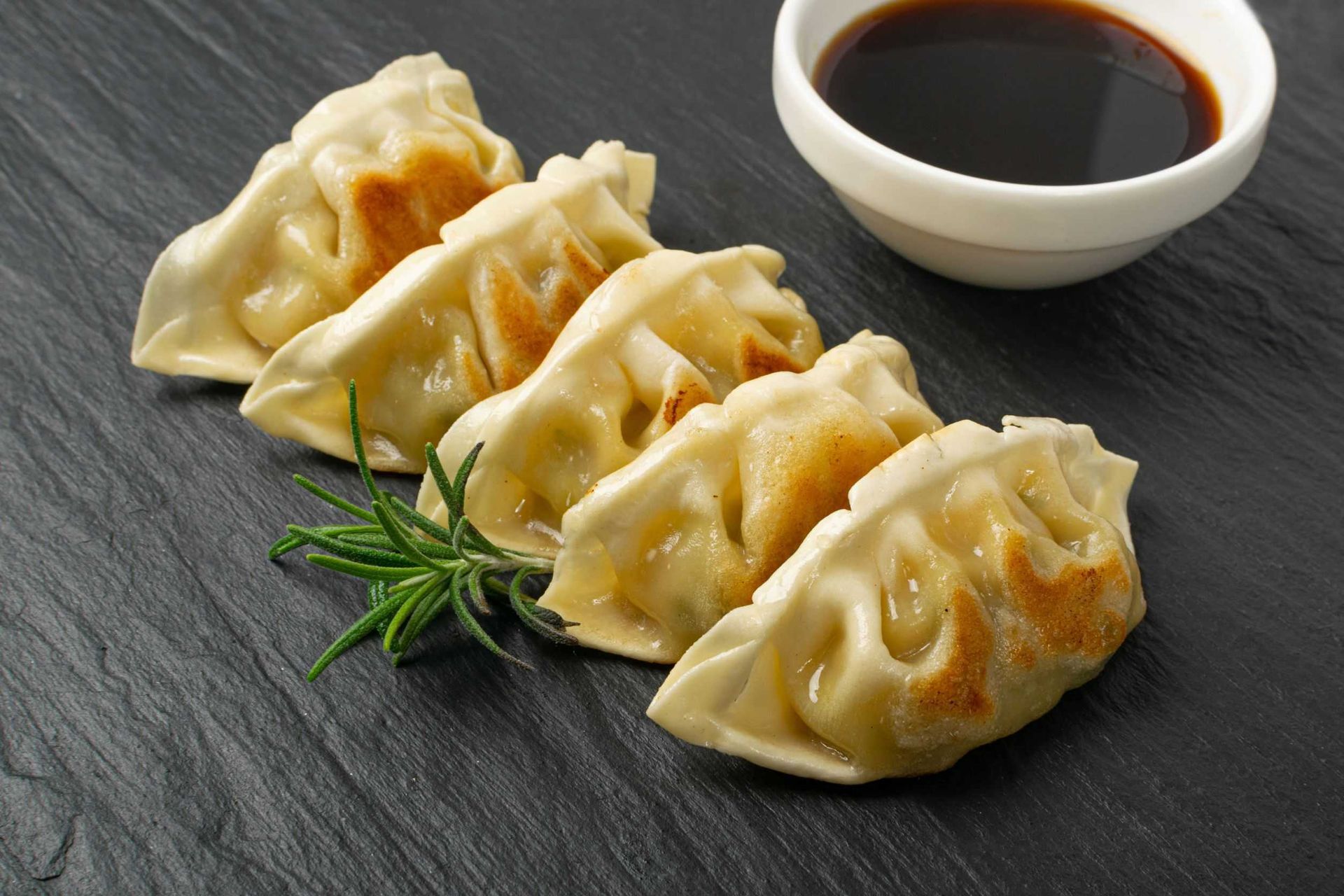 Un plato de empanadillas junto a un bol de salsa de soja.