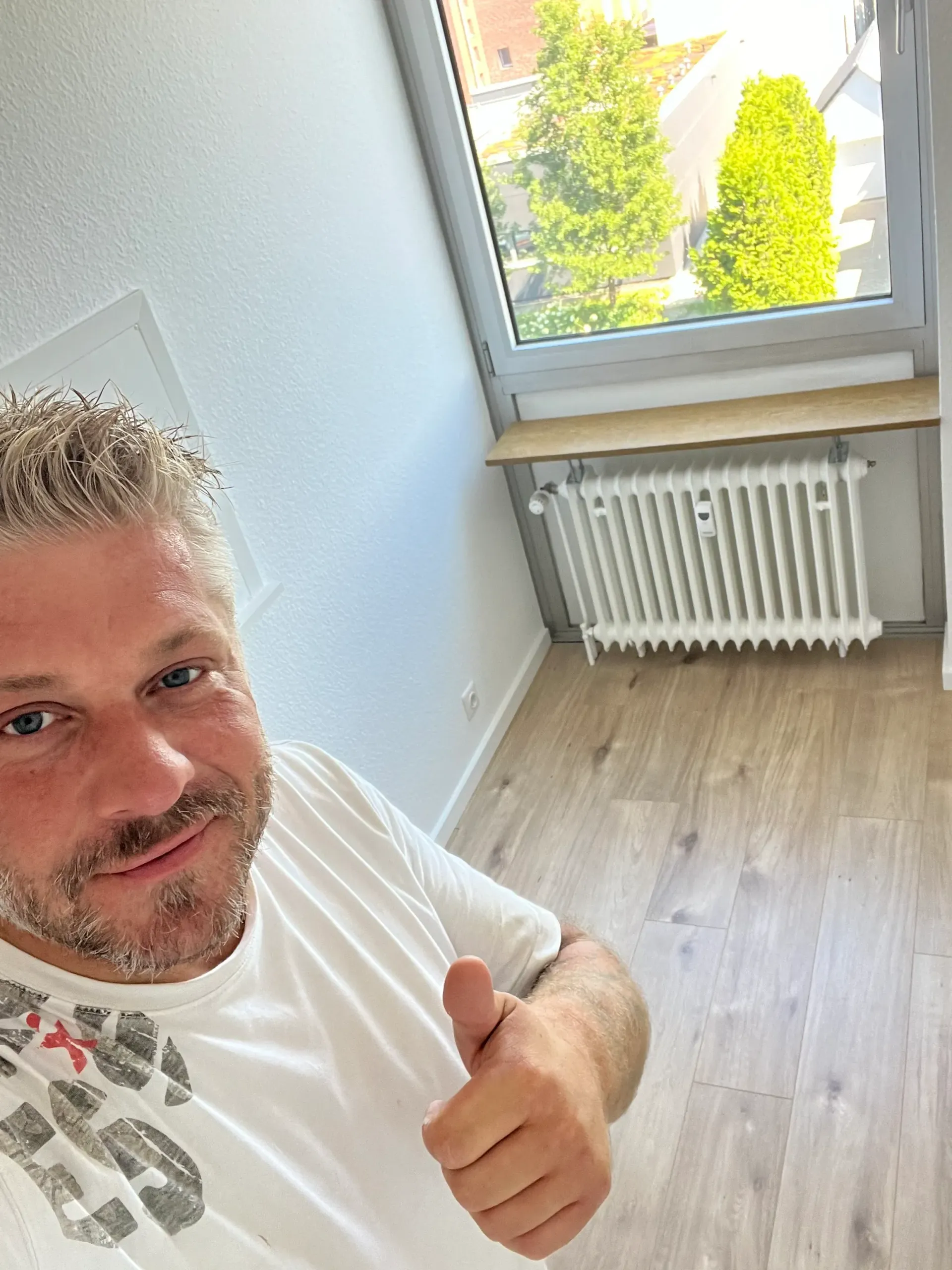 Ein Mann zeigt in einem leeren Raum seinen Daumen nach oben.