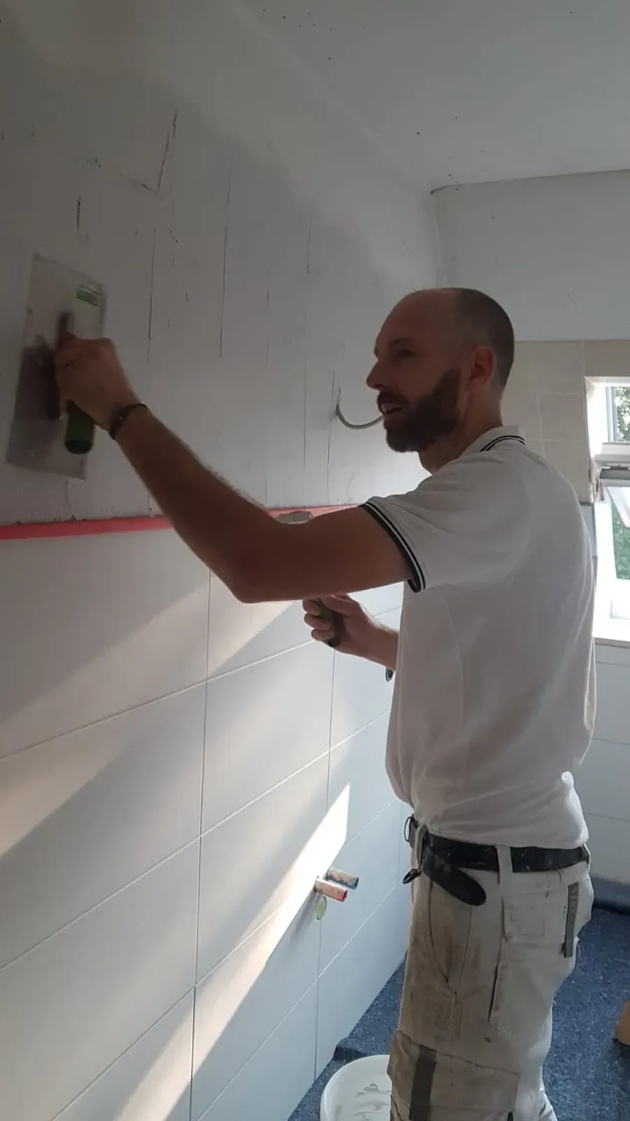 Ein Mann verputzt eine Wand mit einer Kelle.