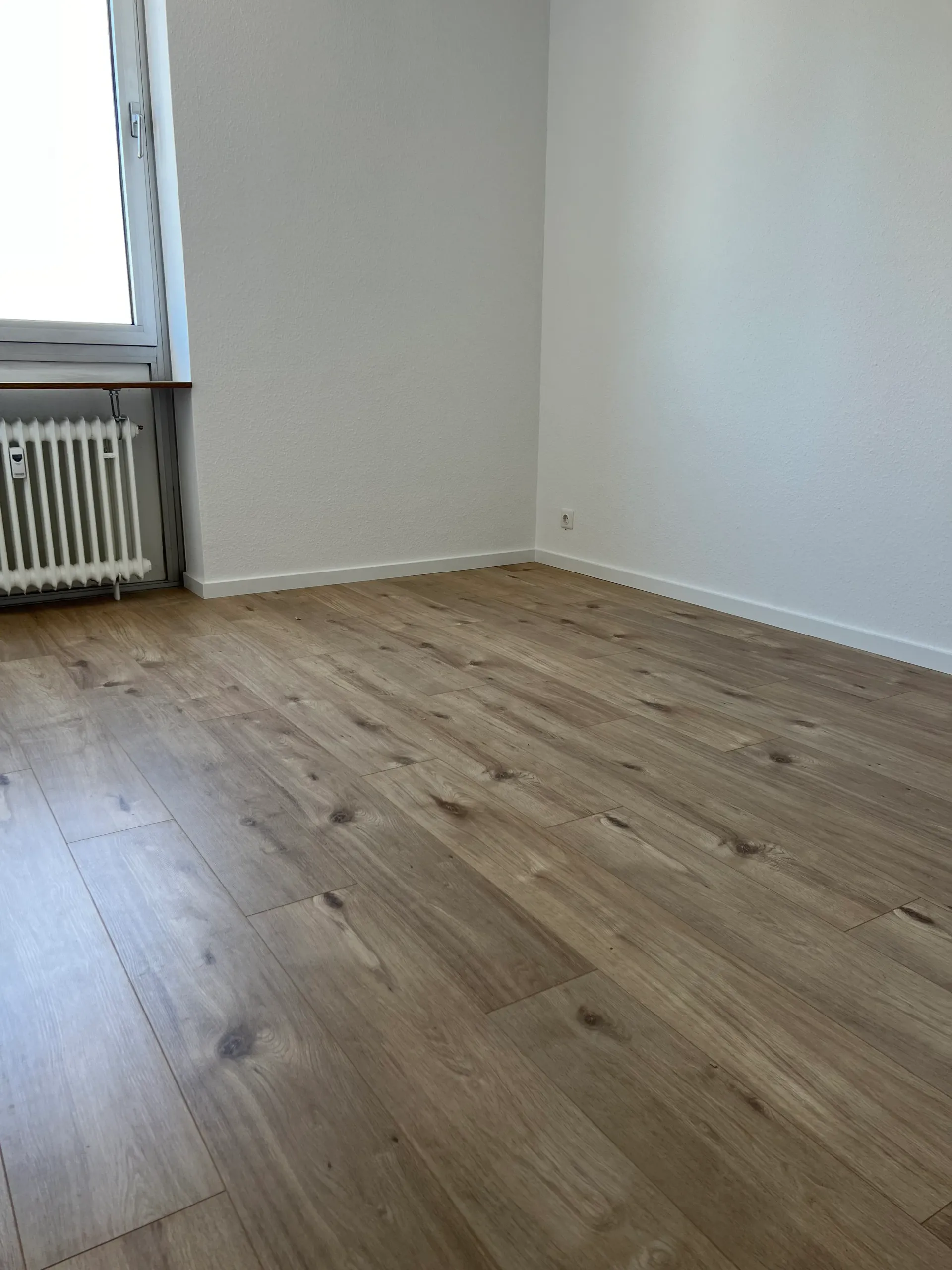 Ein leerer Raum mit Holzboden und Heizkörper.