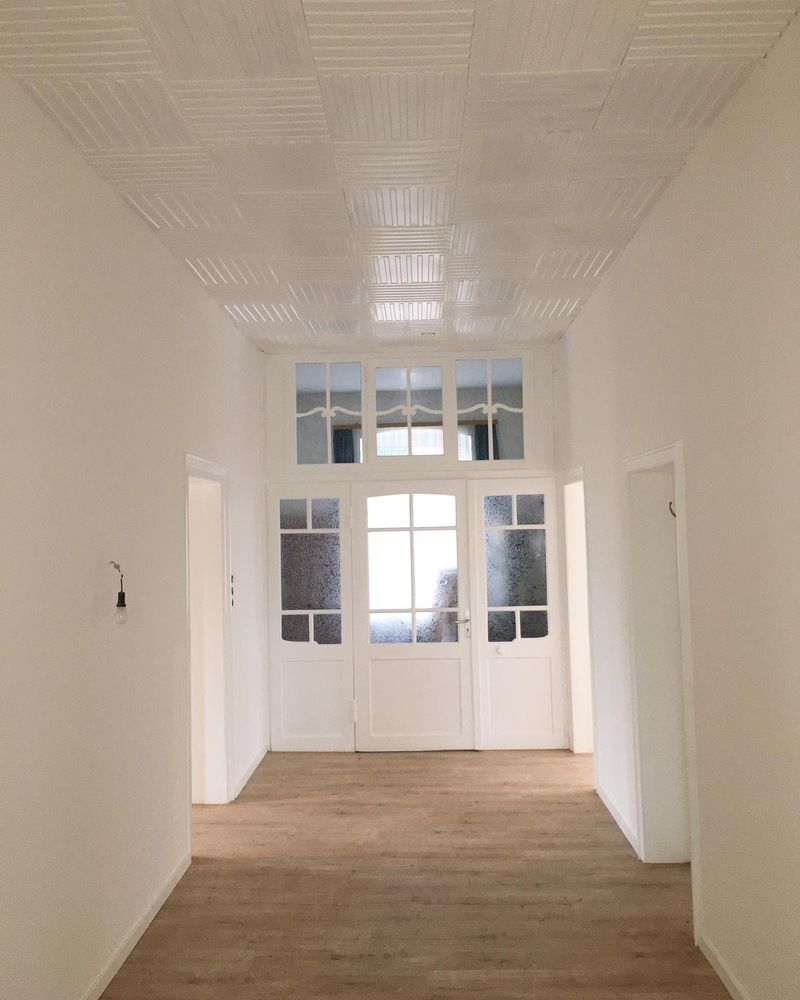 Ein leerer Flur mit weißen Wänden und Holzboden.