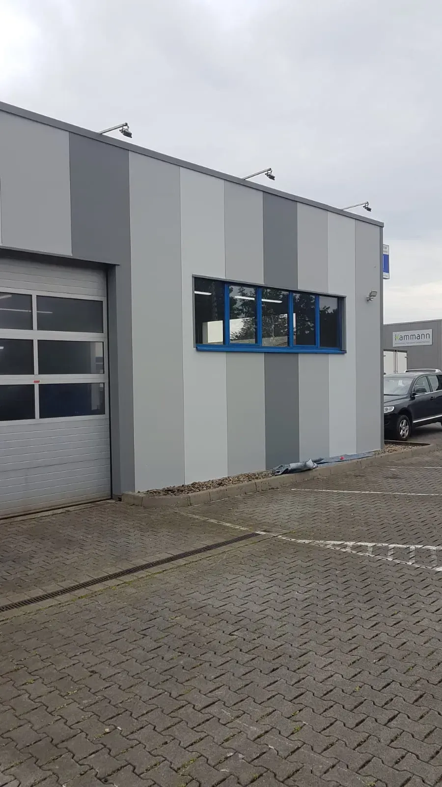 Ein Gebäude mit einem Garagentor und einem davor geparkten Auto.