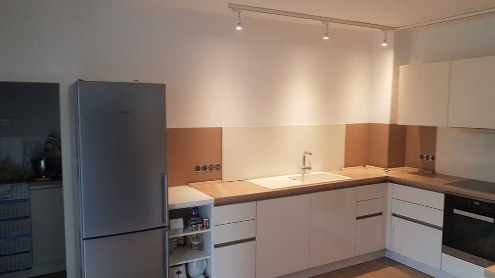 Eine Küche mit weißen Schränken, einem Kühlschrank, einer Spüle und einem Herd.