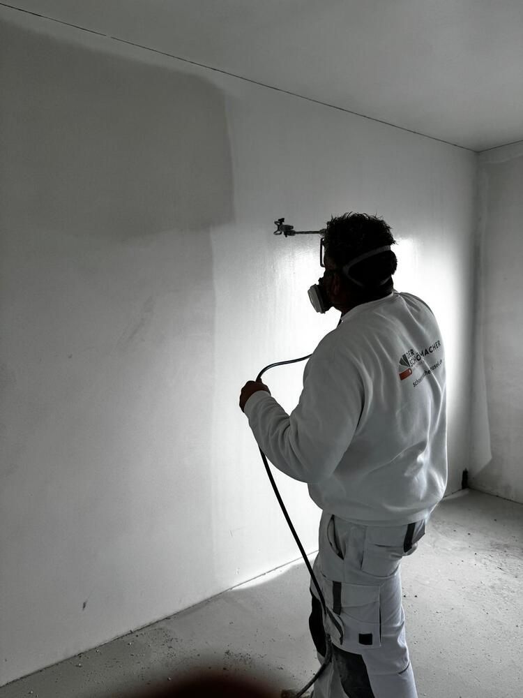 Ein Mann mit einer Maske sprüht Farbe auf eine Wand.