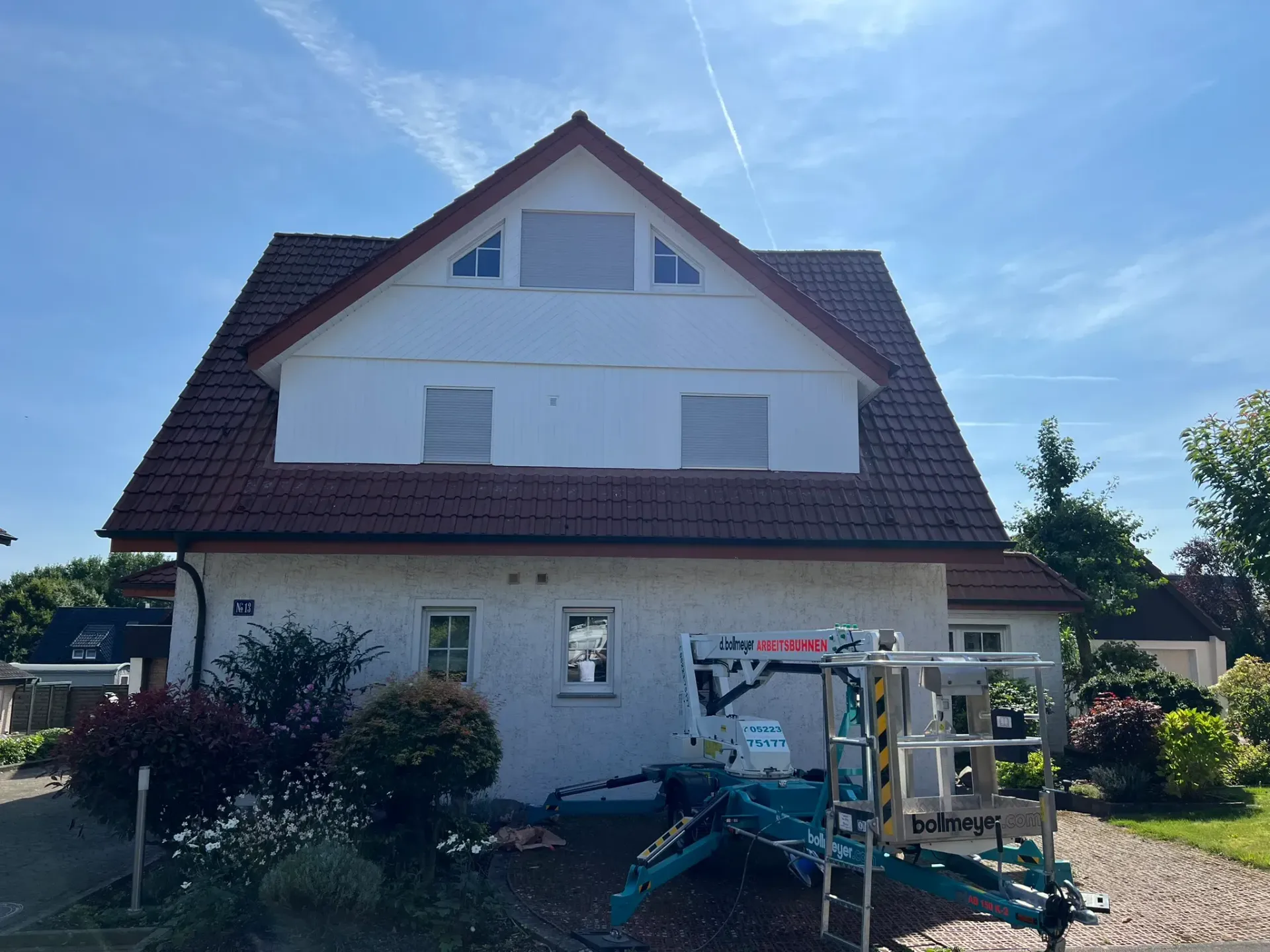 Ein weißes Haus mit einem braunen Dach und einer Leiter davor