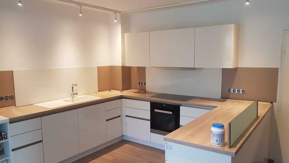 Eine Küche mit weißen Schränken und einer Holzarbeitsplatte.