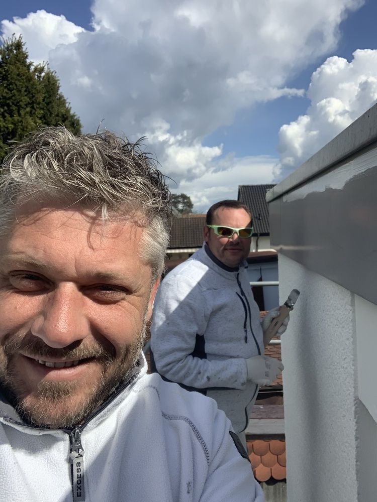 Thomas Neusel und sein Team stehen nebeneinander auf einem Dach und streichen eine Wand.