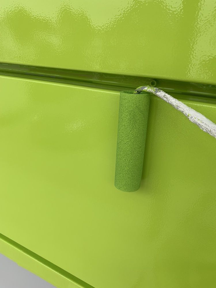 Mit einer grünen Farbrolle wird eine grüne Wand gestrichen.