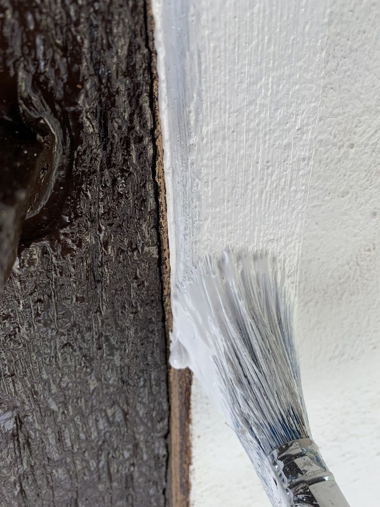 Eine Nahaufnahme eines Pinsels, der eine Wand streicht.