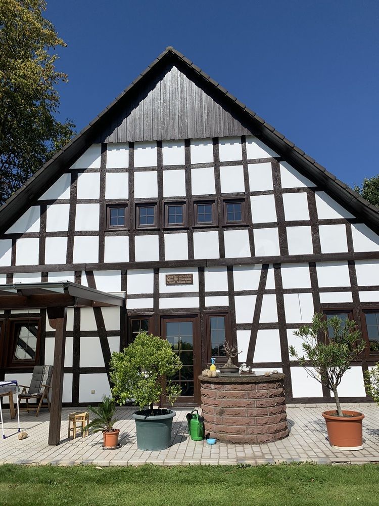 Ein weiß-braunes Haus mit einem Brunnen davor