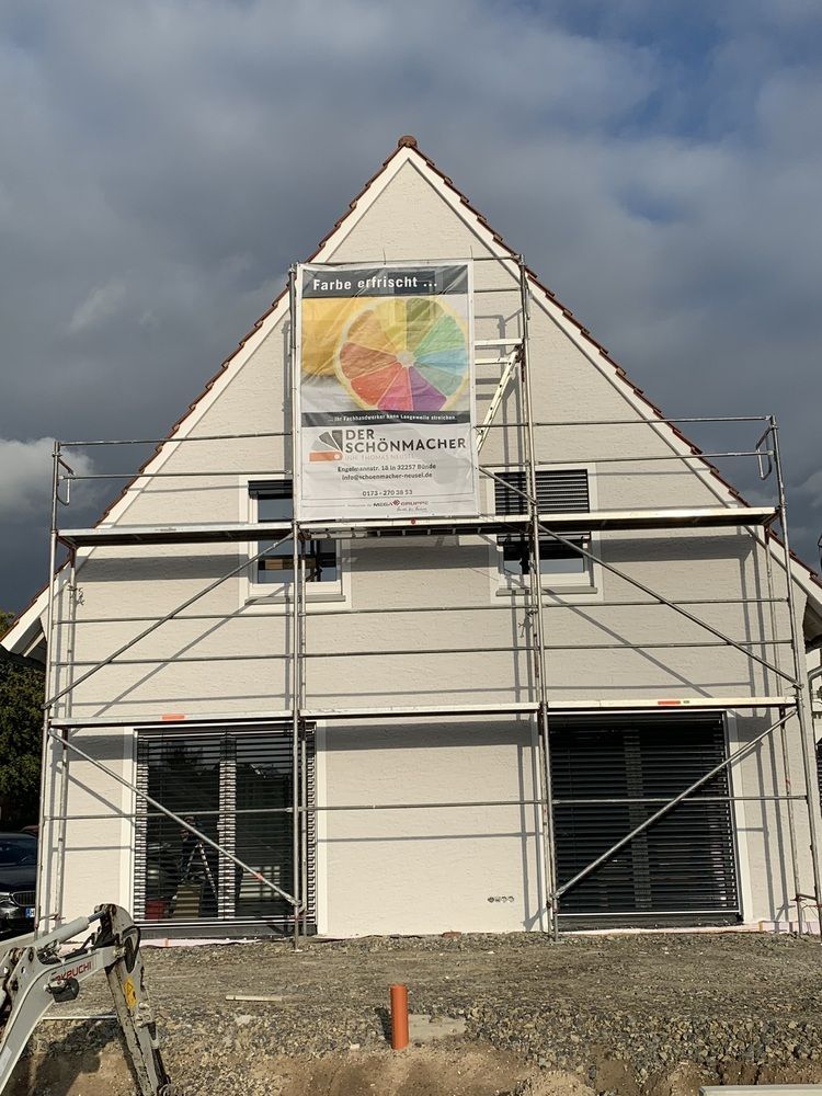 Es wird ein Haus mit Gerüst gebaut, an der Seite hängt ein Schild.