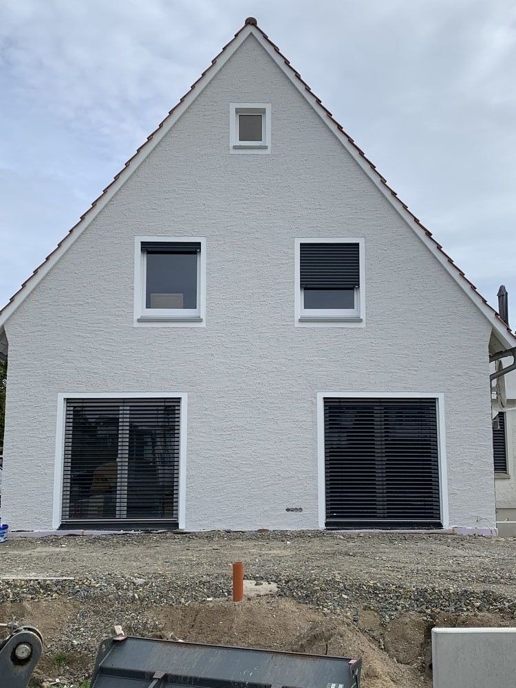 Ein weißes Haus mit schwarzen Jalousien an den Fenstern