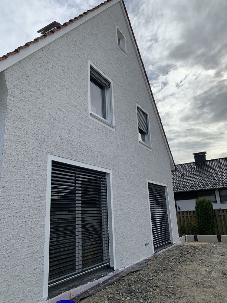 Ein weißes Haus mit schwarzen Jalousien an den Fenstern.
