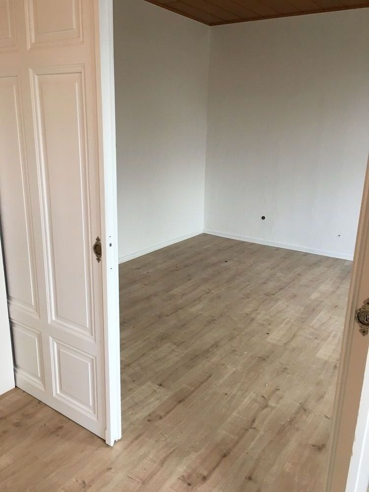 Ein leerer Raum mit Hartholzböden und weißen Wänden.