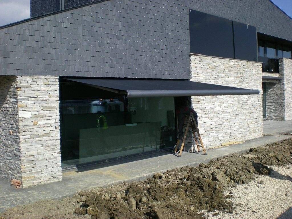 Exterior de casa moderna con revestimiento de piedra y gris oscuro, grandes ventanales