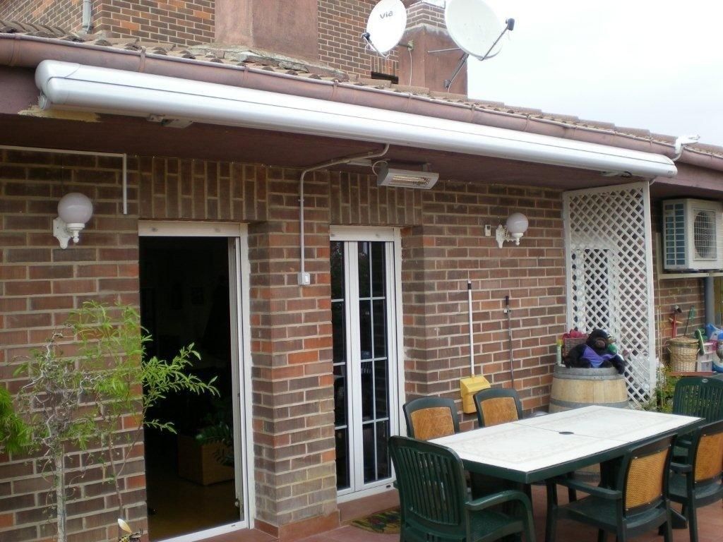 Patio de ladrillo con mesa y sillas de exterior junto a una puerta y ventana de la casa bajo un patio cubierto.
