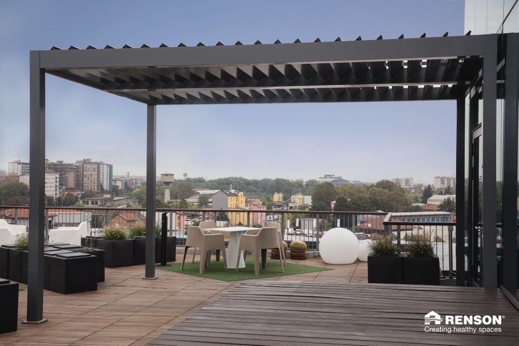 Terraza en la azotea con pérgola, asientos al aire libre y vistas al horizonte de la ciudad al atardecer.