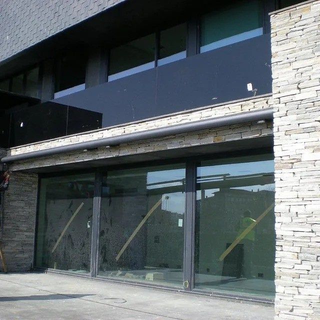 Edificio moderno con exterior de grandes ventanales de cristal y fachada de piedra.