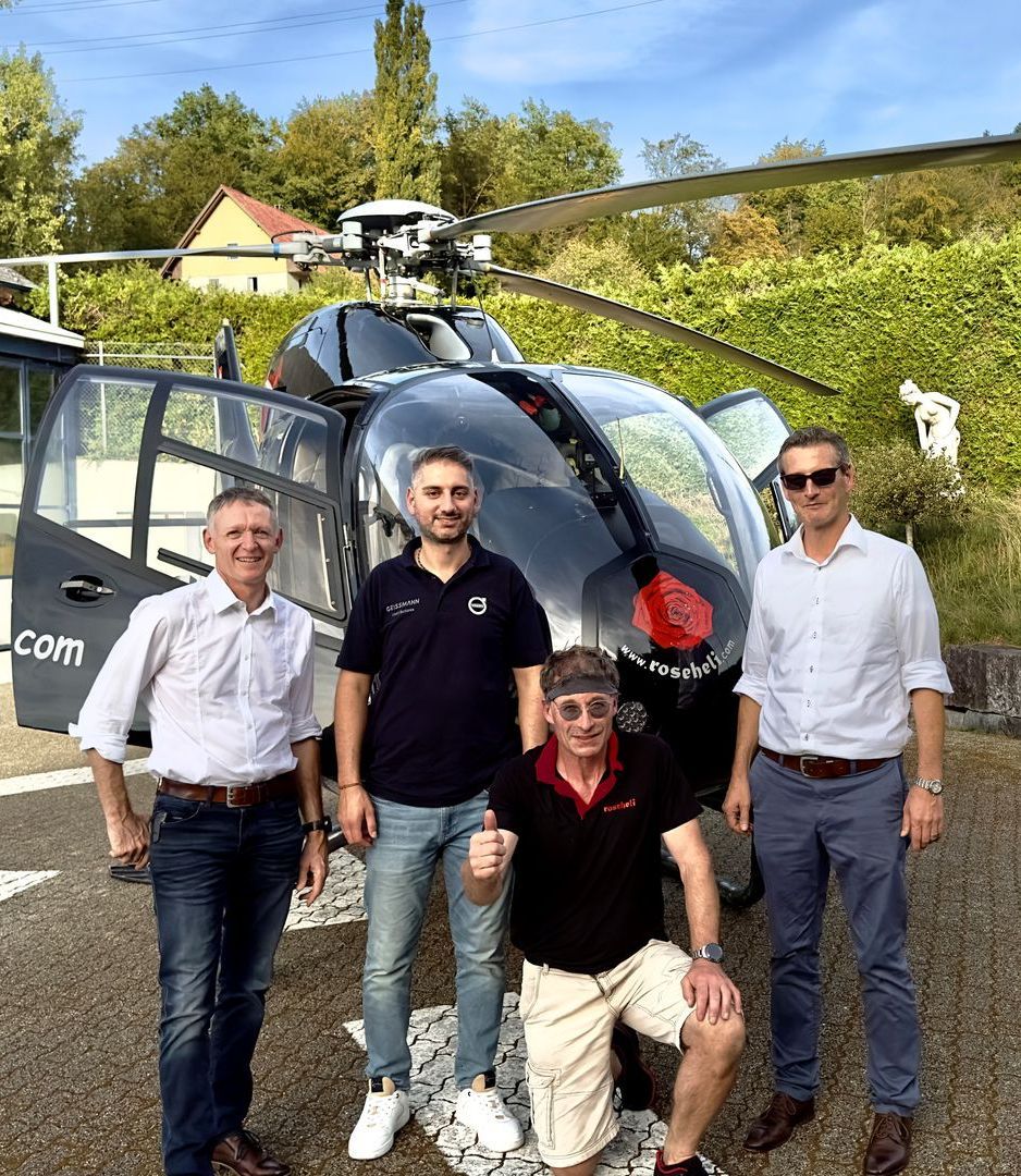 Eine Gruppe Männer steht vor einem Hubschrauber.