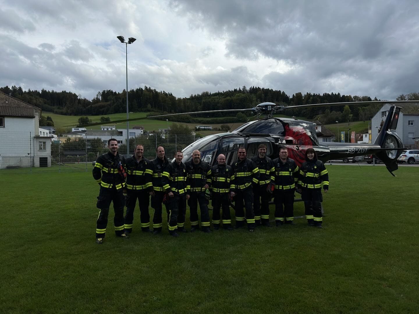 Eine Gruppe Feuerwehrleute posiert für ein Foto vor einem Hubschrauber