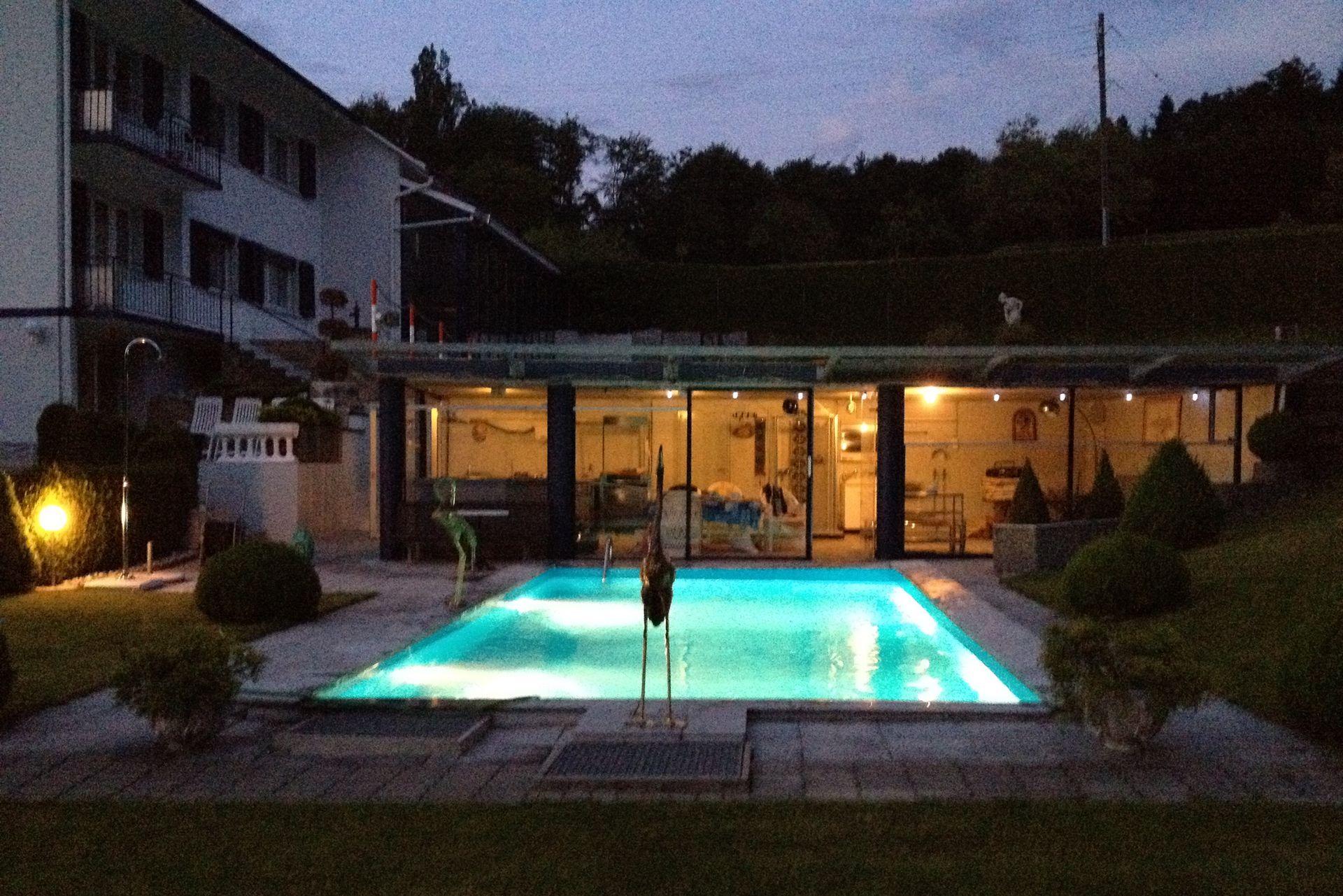 Ein großes Schwimmbad ist nachts vor einem Gebäude beleuchtet