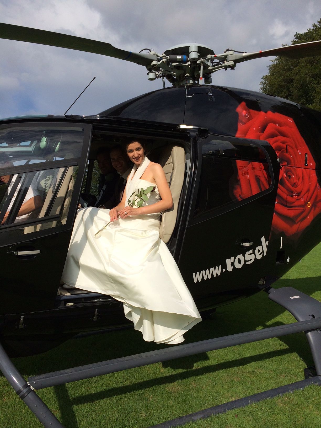 Eine Braut im Hochzeitskleid steigt aus einem Hubschrauber.