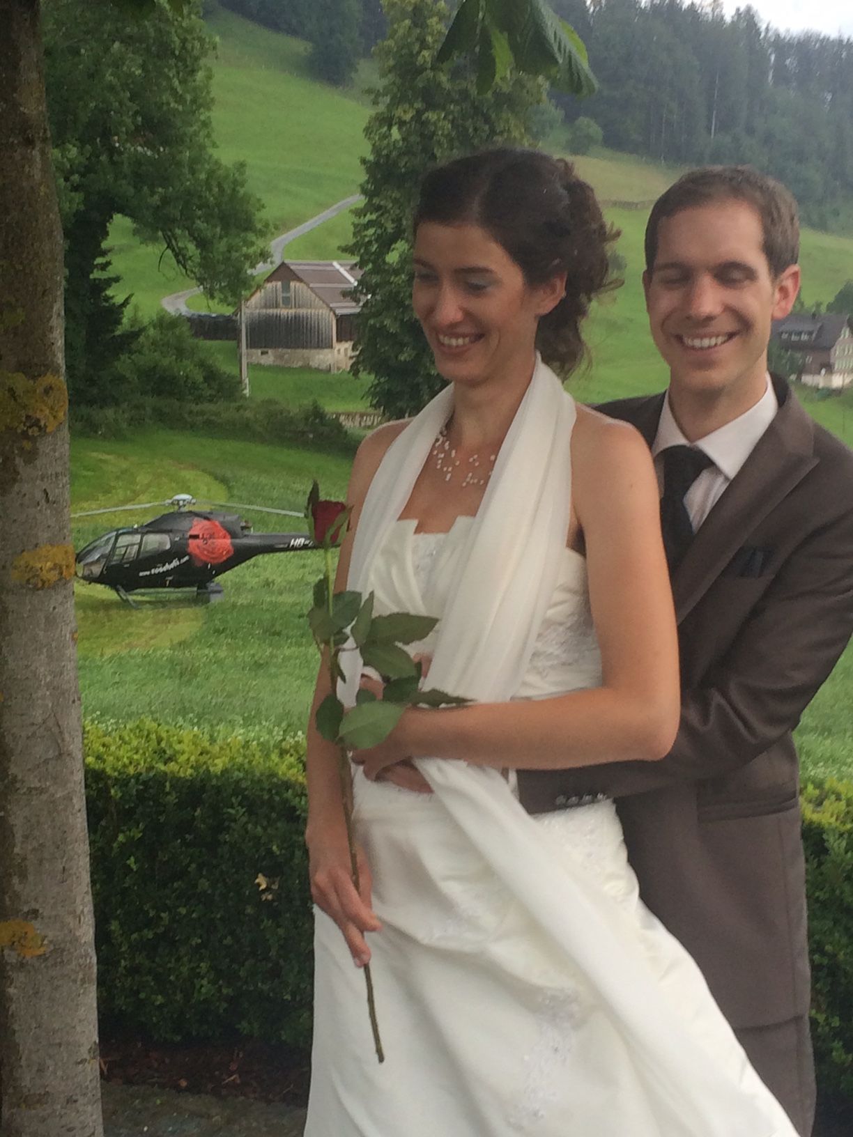 Braut und Bräutigam posieren für ein Foto mit einem Hubschrauber im Hintergrund