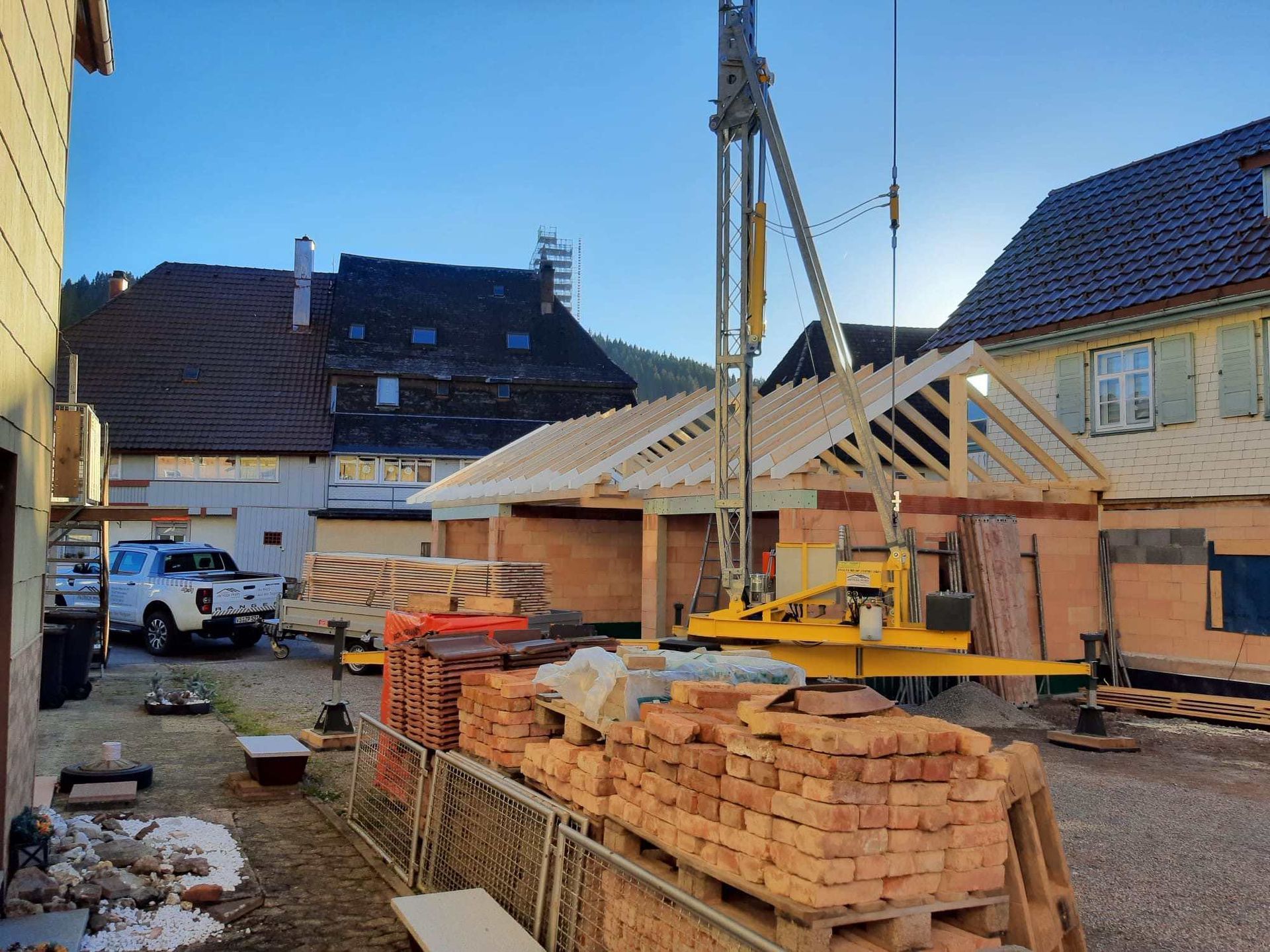 Eine Baustelle mit einem Kran, der ein Stück Holz anhebt, Zimmerei Patrick Pfaff