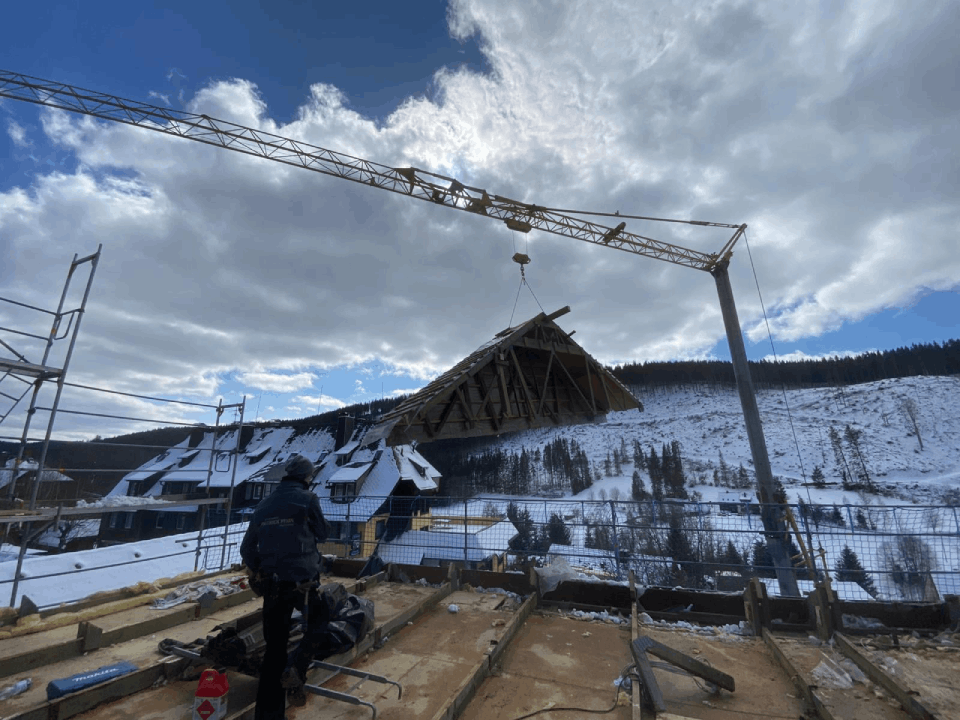 Eine Baustelle mit einem Kran, der ein Stück Holz anhebt, Zimmerei Patrick Pfaff