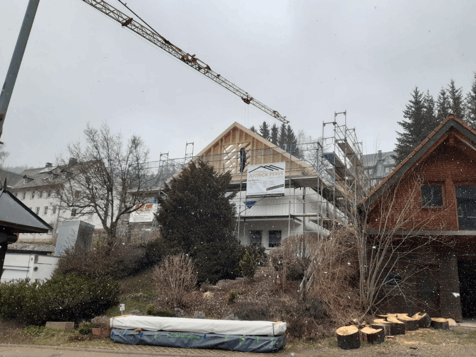 Ein im Bau befindliches Gebäude mit einem Kran im Hintergrund, Zimmerei Patrick Pfaff