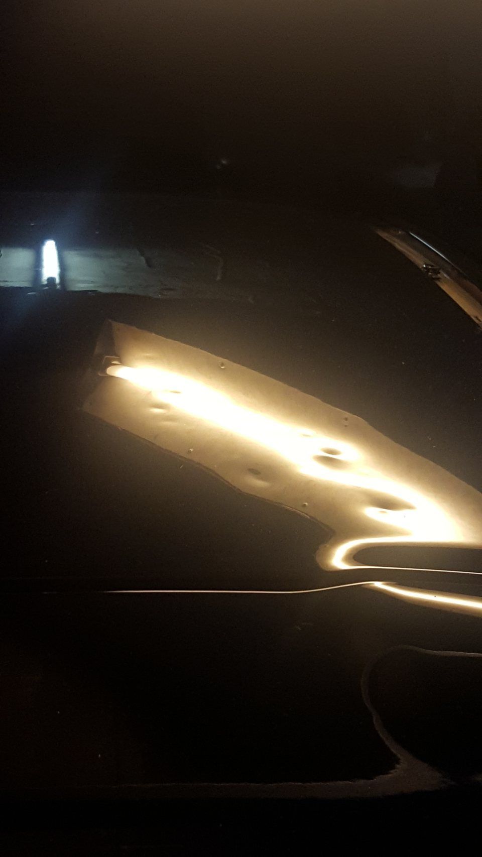 Ein Auto fährt nachts eine dunkle Strasse entlang.