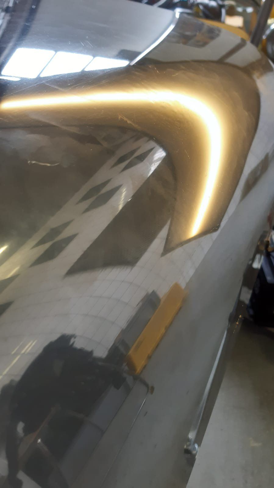 Ein Auto mit einer Delle in der Motorhaube steht in einer Garage.