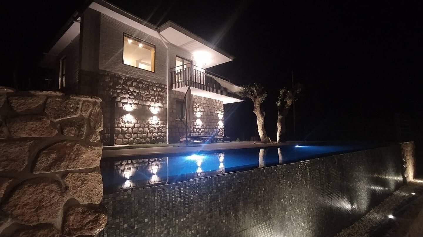 Una casa con piscina delante de ella por la noche.