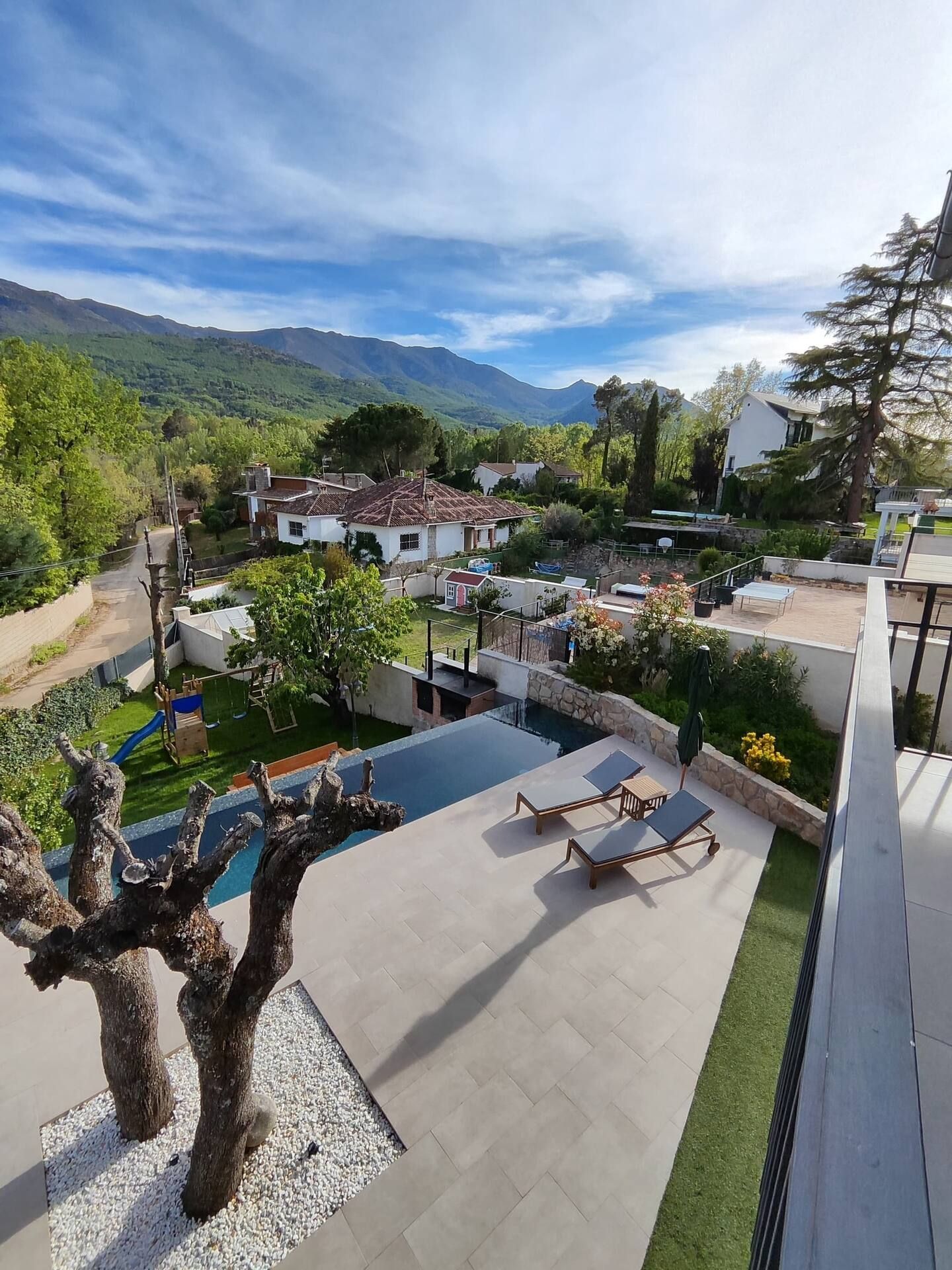 Una vista aérea de una casa con piscina y montañas al fondo.
