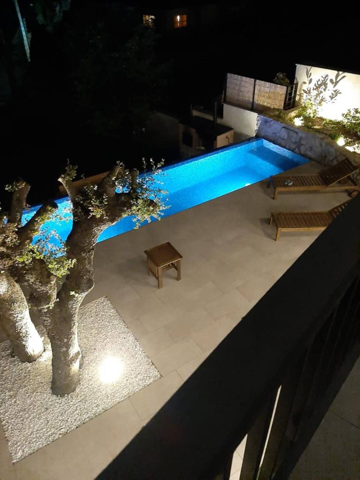 Una vista aérea de una piscina por la noche con un árbol en el medio.