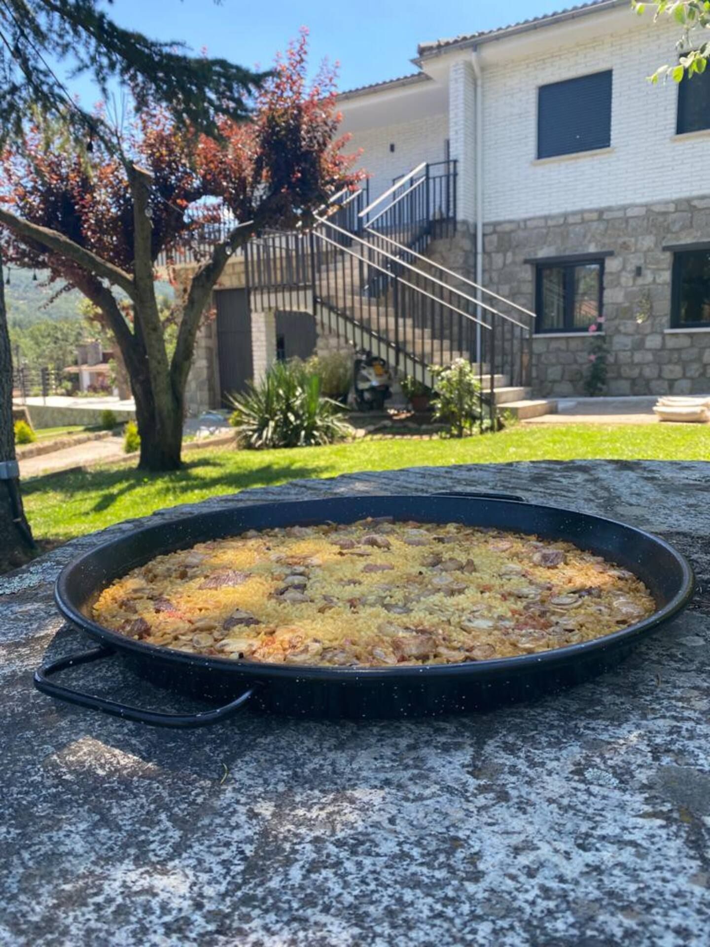 Una gran olla con comida está sobre una roca frente a una casa.