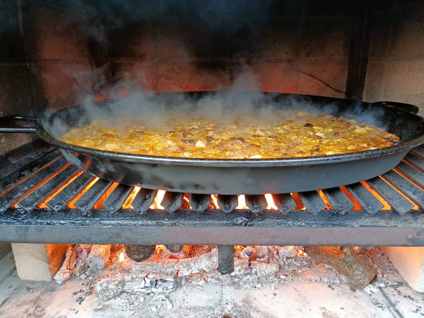 Una sartén con comida se está cocinando en una parrilla sobre un fuego.