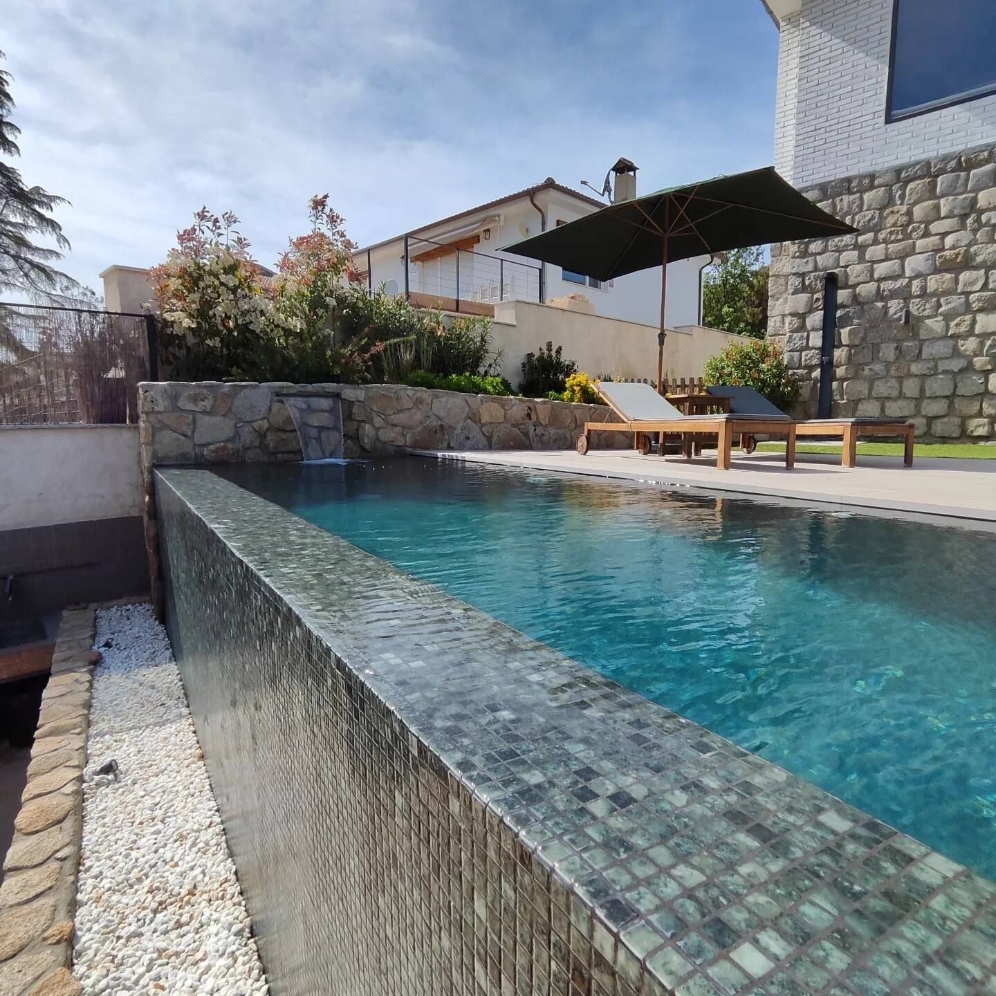 Una gran piscina rodeada de sillas y sombrillas.