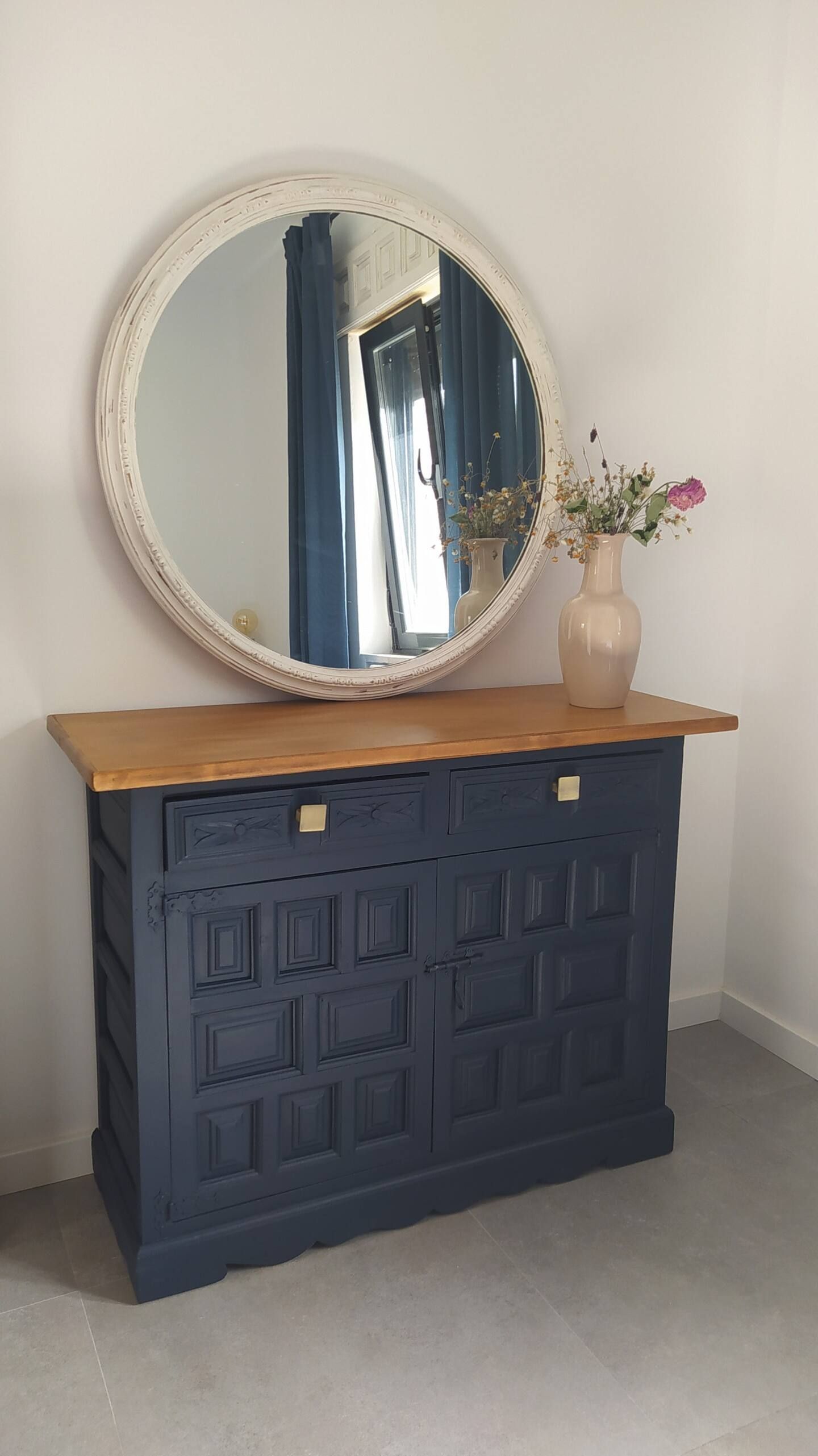Una cómoda azul con un espejo redondo encima en una habitación.