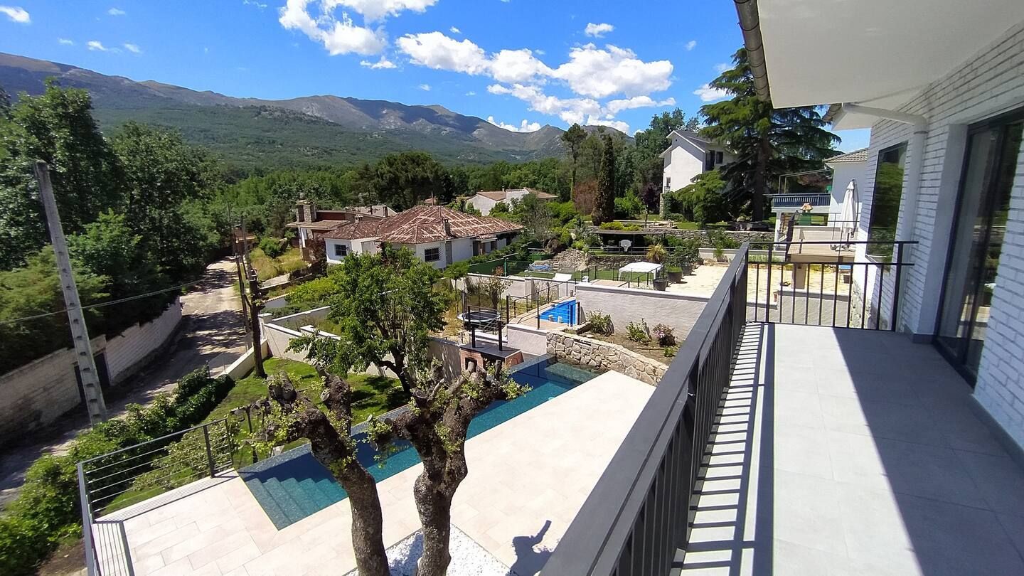 Un balcón con vistas a una piscina con montañas al fondo.