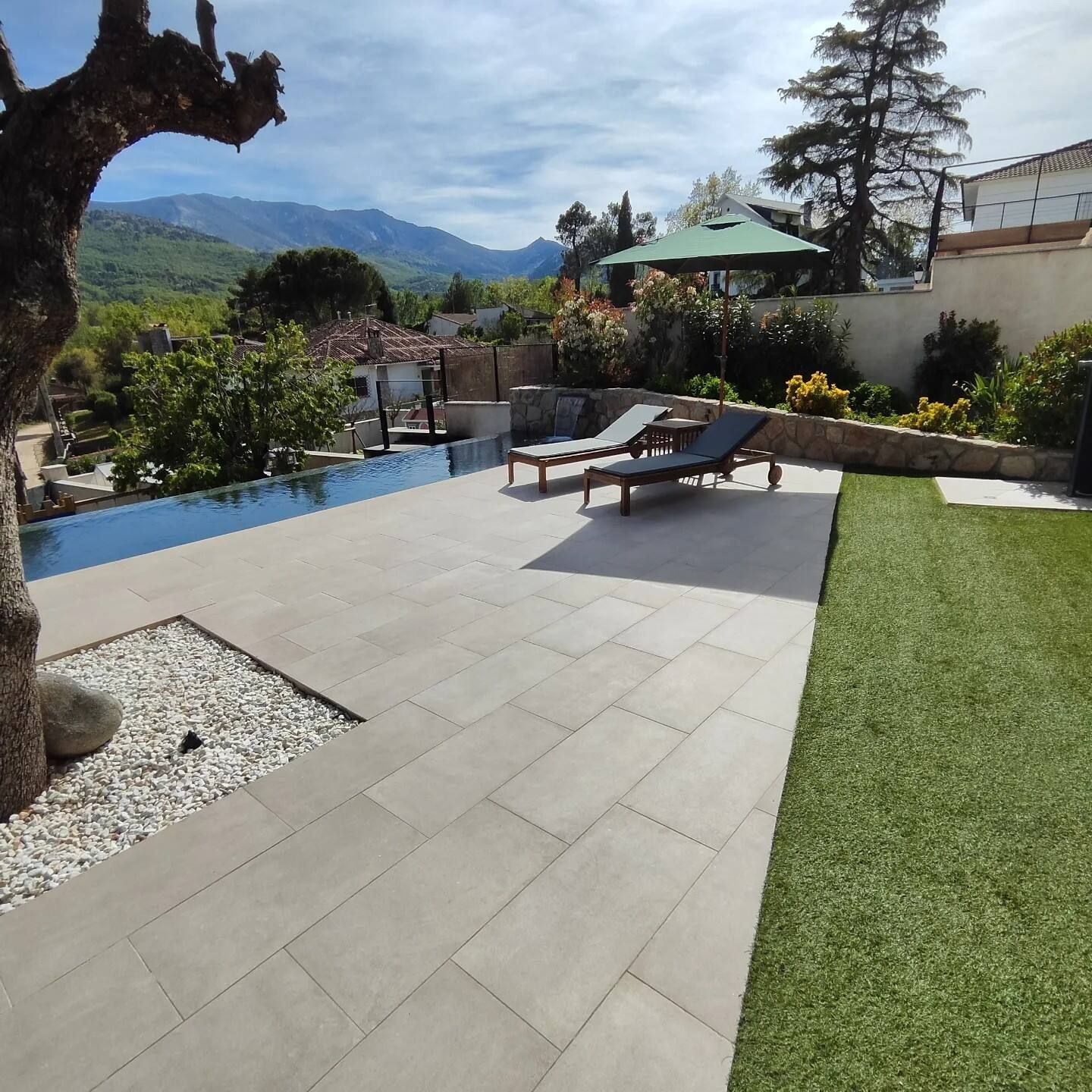 Un patio con sillas y una sombrilla con montañas al fondo.