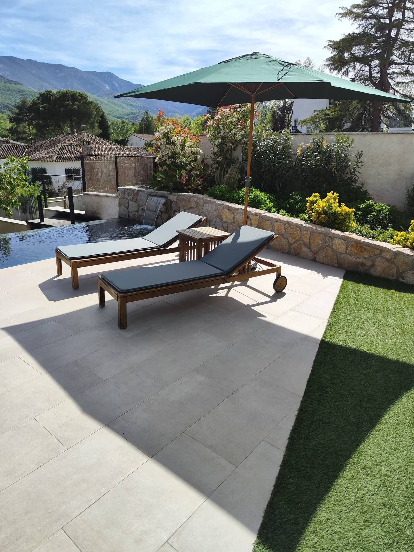 Un patio con dos tumbonas y una sombrilla verde.