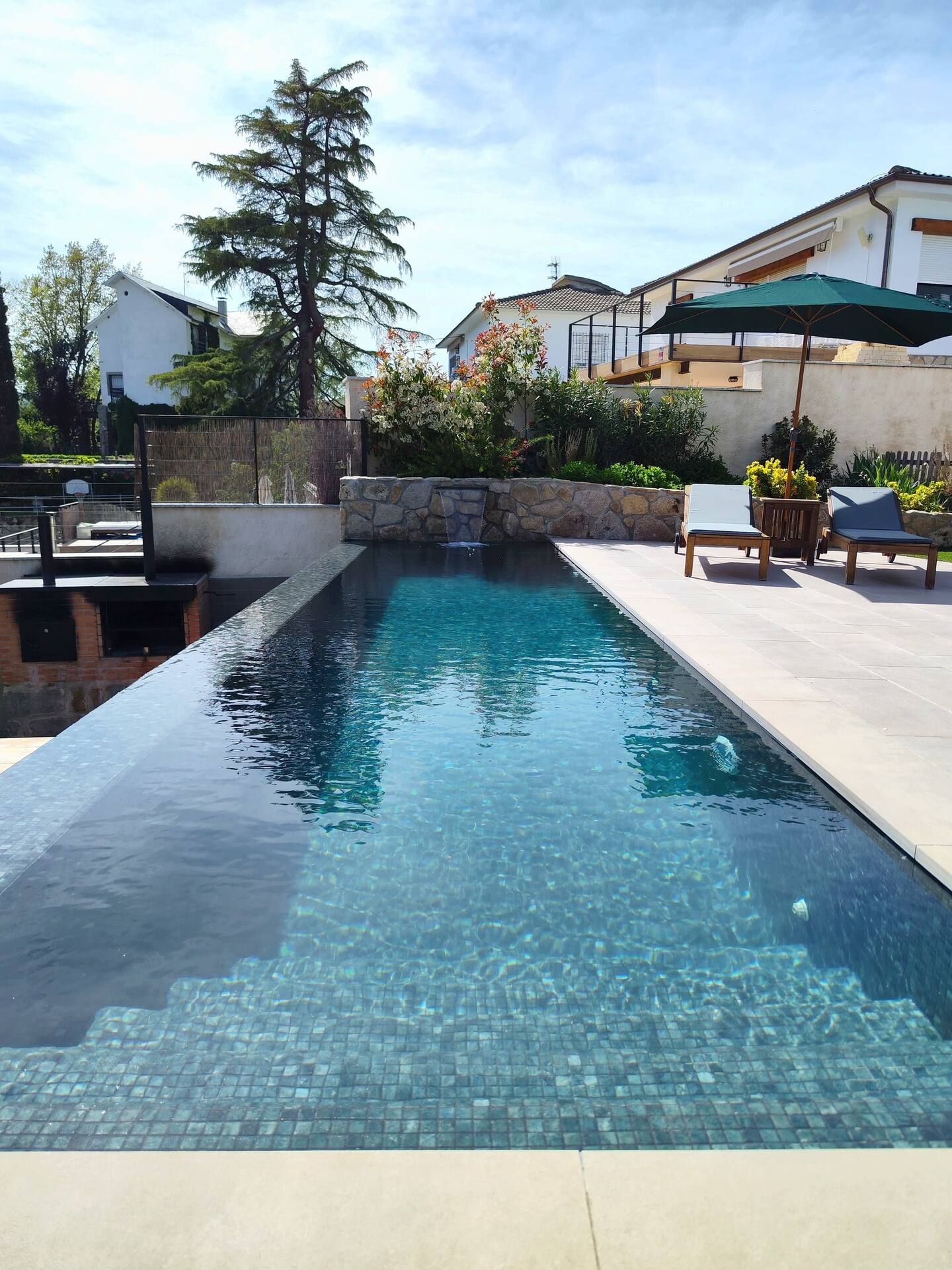 Una gran piscina está rodeada de sillas y sombrillas.